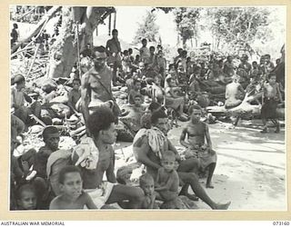 ALEXISHAFEN, NEW GUINEA. 1944-05-15. NEW GUINEA NATIVES WAITING TO BE FERRIED TO ADMOSIN ISLAND, THE TEMPORARY AUSTRALIAN NEW GUINEA ADMINISTRATIVE UNIT HEADQUARTERS, IN RESPONSE TO A CALL MADE TO ..