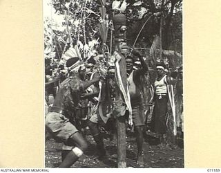 SONG RIVER, FINSCHHAFEN AREA, NEW GUINEA. 1944-03-26. MARKHAM RIVER BOYS DANCING AROUND A TOTEM POLE DURING A NATIVE SING-SING IN THE AUSTRALIAN NEW GUINEA ADMINISTRATIVE UNIT (ANGAU) COMPOUND TO ..