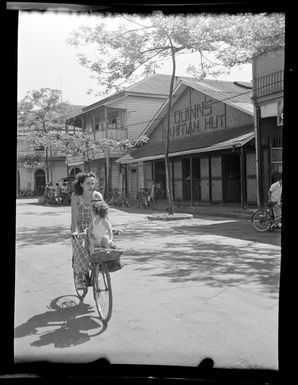 Street scene with woman riding bicycle with toddler, Papeete, Tahiti