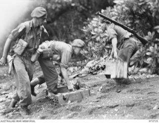 KARKAR ISLAND, NEW GUINEA. 1944-06-02. AMMUNITION CARRIERS OF THE 37/52ND INFANTRY BATTALION PICK UP RIFLE AMMUNITION FROM THE BEACH DURING THEIR BEACH LANDING ON THE ISLAND. IDENTIFIED PERSONNEL ..