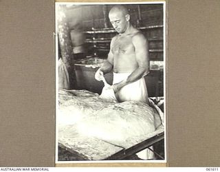 DUMPU, RAMU VALLEY, NEW GUINEA. 1943-11-24. NX197107 PRIVATE E. K. GLADMORE OF BATEMAN'S BAY, NSW, A BAKER OF THE 4TH AUSTRALIAN FIELD BAKERY WORKING UP DOUGH IN THE BAKEHOUSE