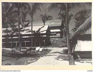 JACQUINOT BAY, NEW BRITAIN. 1945-06-09. BUILDING TYPES AT 2/8 GENERAL HOSPITAL, AT 5 BASE SUB-AREA. THE SISTERS' SICK BAY IS THE THATCHED HUT IN THE FOREGROUND. ON THE LEFT ARE PLANNED AND PREPARED ..