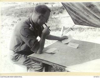 ALEXISHAFEN, NEW GUINEA. 1944-05-27. NX112724 CAPTAIN G.H. NICHOLLS IN A TENT COVERED POLLING BOOTH AT HEADQUARTERS 8TH INFANTRY BRIGADE, RECORDING HIS VOTE IN THE NEW SOUTH WALES STATE ELECTIONS