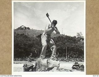 ELA BEACH, NEW GUINEA. 1944-01-01. V102962 CORPORAL W. H. BENNETT OF THE NEW GUINEA FORCE PROVOST COMPANY COMPETING IN THE 12" UNDERHAND WOOD CHOP AT THE ALLIED SERVICES GRAND SPORTS CARNIVAL