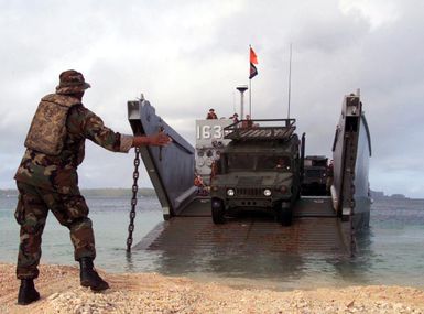 Boatswains Mate 3 (BM3) John Grant, a Beach MASTER with Unit 1, guides an M998 High-Mobility Multipurpose Wheeled Vehicle (HMMWV), onto a Landing Craft Utility (LCU) 1634 during an offload exercise at the Inner Apra Harbor on the island of Guam, in support of Exercise TANDEM THRUST 2003