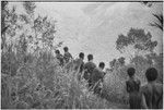 Mortuary ritual: women, their faces and bodies smeared with clay as sign or mourning, carry corpse wrapped for burial