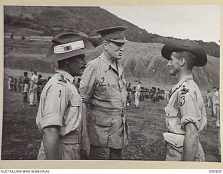NEAR NADZAB, NEW GUINEA. 1945-03-26. LORD WAKEHURST, GOVERNOR OF NEW SOUTH WALES (2), ACCOMPANIED BY CAPTAIN A.I. GAY, OFFICER COMMANDING B COMPANY, 2 NEW GUINEA INFANTRY BATTALION (1), SPEAKING ..
