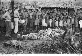 SERGEANT J. RANGER, A MEMBER OF THE 39TH SUPPLY DEPOT COMPANY AT LAE (1), WITH NX100451 WARRANT OFFICER II, F.H. THRESHER, AUSTRALIAN NEW GUINEA ADMINISTRATIVE UNIT (2), BARTERING WITH NATIVES. THE ..