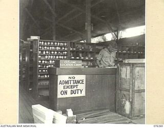 LAE, NEW GUINEA. 1944-09-27. A STOREMAN AT WORK IN ONE OF THE SPARE PARTS STORES OF THE 43RD FIELD ORDNANCE DEPOT