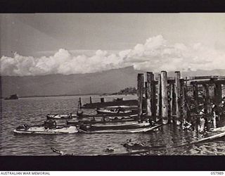 LAE, NEW GUINEA. 1943-10-12. SUNKEN JAPANESE BARGES AT THE OLD PRE-WAR WHARF. IN THE BACKGROUND AT LEFT IS JAPANESE WRECK V.S. TUG CAM