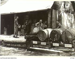 TROOPS OF THE 27TH INFANTRY BATTALION WORKING IN THE REGIMENTAL BULK STORE OF THE 23RD INFANTRY BRIGADE. IDENTIFIED PERSONNEL ARE:- SX37882 LANCE-CORPORAL C.H. GREENING (1); S21361 PRIVATE E.N. ..