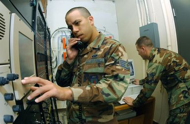 US Air Force (USAF) STAFF Sergeant (SSGT) Edgardo Dizon (front) and SENIOR AIRMAN (SRA) Matthew Copps work on the Enhanced Terminal Voice Switch (ETVS) at Andersen Air Force Base (AFB), Guam. The ETVS controls all radio and telephone systems needed to control air traffic