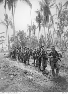 SATTELBERG AREA, NEW GUINEA. 1943-11-15. B COMPANY, 2/2ND AUSTRALIAN MACHINE GUN BATTALION MOVING TO THE FRONT LINE THROUGH MUD AND SLUSH: PRIVATE CHURCHYARD IS LEADING, FOLLOWED BY SERGEANT WEBB