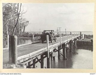 BOUGAINVILLE. 1945-05-30. A JEEP CROSSING THE ADELE RIVER ON A PILE DRIVER BRIDGE CONSTRUCTED BY 11 FIELD COMPANY ROYAL AUSTRALIAN ENGINEERS. THREE-TON VEHICLES LOADED WITH STORES CAN NOW COMPLETE ..