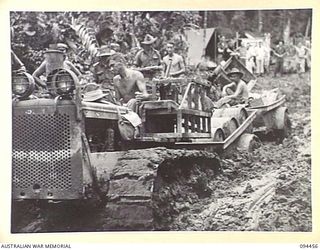 SOUTH BOUGAINVILLE. 1945-07-29. A TRACTOR TOWING TWO JEEP TRAILERS LOADED WITH STORES THROUGH HEAVY MUD ON THE BUIN ROAD, IN 2 FIELD REGIMENT, ROYAL AUSTRALIAN ARMY AREA. THE ROAD, OUR MAIN SUPPLY ..