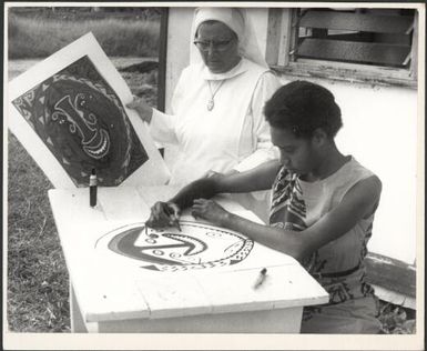 Nun standing beside a young Papuan woman creating an artwork, New Guinea