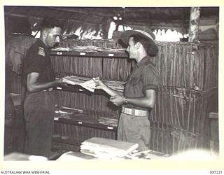 CAPE WOM, NEW GUINEA. 1945-09-29. LIEUTENANT R.W. GRUBB, AUSTRALIAN ARMY EDUCATION SERVICE, HEADQUARTERS 6 DIVISION, ACCEPTING GRAMOPHONE RECORDS WHICH HAVE BEEN OUT ON LOAN FROM CORPORAL C.C. ..