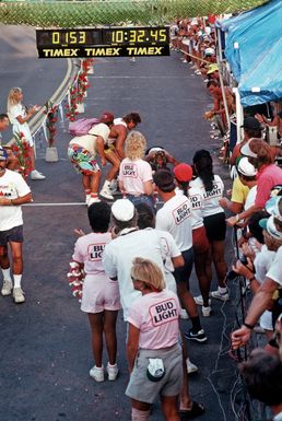 Onlookers encourage an exhausted contestant attempting to cross the finish line after completing the 26-mile marathon, part of the 1987 Ironman Competition