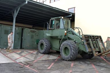 US Marine Corps (USMC) Sergeant (SGT) Wills, assigned to Combat Service Support Group 3 (CSSG-3), Marine Forces Pacific (MARFORPAC) uses a Rough Terrain Forklift to tow a Combat Camera and Printing (CC&P) portable transport van to a staging area at Camp H.M. Smith, Hawaii (HI), as the Unit prepares for deployment to Iraq, in support of Operation IRAQI FREEDOM