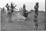 Pig festival, stake-planting, Tuguma: Tsembaga man puts bamboo on fire, when it explodes group will leave for Tuguma