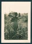 Portrait of unidentified New Guinea man standing holding a rifle over his shoulder and a couple of wallabies on his back, Bulwa, New Guinea, c1929 to 1932