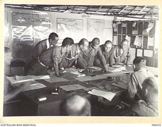 CAPE WOM, NEW GUINEA, 1945-09-13. JAPANESE STAFF OFFICERS EXAMINING MAP ON THE TABLE DURING A CONFERENCE BETWEEN STAFF OFFICERS OF 6 DIVISION, HEADED BY LIEUTENANT-COLONEL J. BISHOP GENERAL STAFF ..