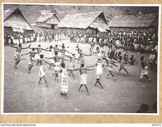 KILA KILA, PAPUA, NEW GUINEA. 1943-12-25. KEREMA BOYS EXECUTING A DANCE AT THE AUSTRALIAN AND NEW GUINEA ADMINISTRATION UNIT NATIVE LABOUR CAMP. THE DANCERS WEAR LONG TRAILS OF GRASS AND FLOWERS, ..