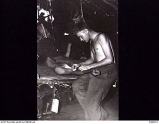 DUMPU, NEW GUINEA. 1943-10-15. QX42621 PRIVATE (PTE) S. V. DOW (1) AND SX13583 PTE R. CROSS (2), MEDICAL ORDERLIES OF THE 2/6TH AUSTRALIAN FIELD AMBULANCE WITH "E" SURGICAL TEAM, GIVING A POST ..