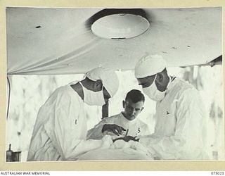 NAGADA, NEW GUINEA. 1944-08-02. THE SURGEON AND HIS ASSISTANTS AT WORK IN THE OPERATING THEATRE OF THE 4TH FIELD AMBULANCE. IDENTIFIED PERSONNEL ARE:- VX106539 SERGEANT L. MCMURRAY (1); VX104318 ..