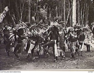 DOBODURA, NEW GUINEA. 1943-10-10. NATIVE CEREMONIAL DANCES IN PROGRESS IN THE VILLAGE CLEARING WERE ATTENDED BY ALLIED TROOPS AND NURSES