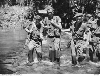 BOUGAINVILLE, 1945-05-18. WALKING WOUNDED OF 57/60 INFANTRY BATTALION INJURED IN THE ADVANCE ALONG COMMANDO ROAD, BEING ASSISTED BY TROOPS ACROSS THE FORD AT THE HONGORAI RIVER DURING THEIR ..