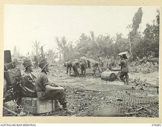 JACQUINOT BAY, NEW BRITAIN. 1944-11-05. TROOPS OF THE 6TH BRIGADE WORKING UNDER VERY ADVERSE CONDITIONS TO GET THEIR STORES AND EQUIPMENT UNDER COVER