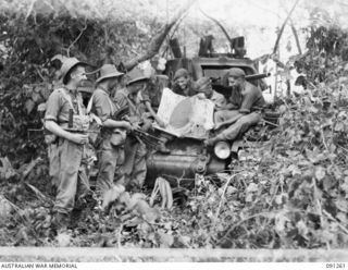 AITAPE-WEWAK SECTOR, NEW GUINEA. 1945-04-26. PERSONNEL OF 2/3 INFANTRY BATTALION AND 2/4 ARMOURED REGIMENT SHARING SOUVENIRS AT KALIMBOA VILLAGE. IDENTIFIED PERSONNEL ARE:- PRIVATE E.S. MCDONALD ..