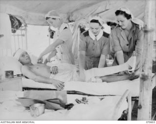 TWO AUSTRALIAN ARMY NURSING SERVICE (AANS) SISTERS, AND A MEMBER OF THE AUSTRALIAN ARMY MEDICAL WOMEN'S SERVICE (AAMWS) ATTENDING A PATIENT WITH MULTIPLE INJURIES AT THE 2/1ST AUSTRALIAN GENERAL ..