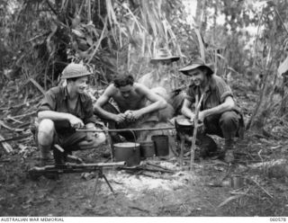 SATTELBERG AREA, NEW GUINEA. 1943-11-15. INFANTRYMEN OF THE 2/24TH AUSTRALIAN INFANTRY BATTALION PREPARING AN EVENING MEAL DURING THE BATTLE FOR SATTELBERG. LEFT TO RIGHT: VX48214 PRIVATE A. C. ..