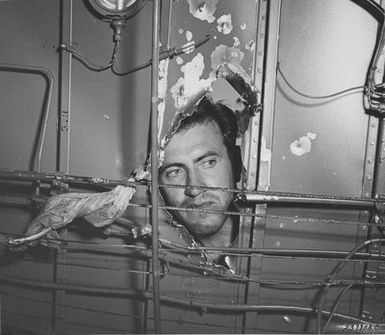 Photograph of Lt. Lou Zamperini, Bombardier, Examining the Damage a Japanese Cannon Shell did to His Liberator