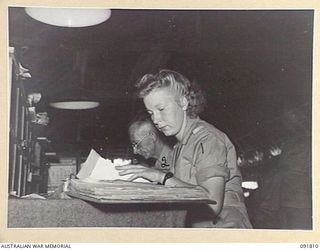 LAE, NEW GUINEA. 1945-05-15. PRIVATE S. MASLEN (1), AT WORK IN THE GENERAL REGISTRY, A BRANCH, HEADQUARTERS FIRST ARMY, WITH CORPORAL E. DOHERTY (2). A FEW DAYS AFTER THEIR ARRIVAL FROM AUSTRALIA ..