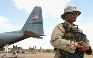 US Army (USA) SPECIALIST Fourth Class (SPC) Tulen Nena, armed with a KAC 5.56 mm Modular Weapon System (MWS) Special Operation Peculiar Modification (SOPMOD) M4, stands guard on the flight line as equipment is off-loaded from a US Air Force (USAF) C-130 Hercules aircraft in Gode, Ethiopia, during Operation IRAQI FREEDOM. SPC Nena is deployed to Combined Joint Task Force-Horn of Africa (CJTF-HOA) from the 1ST Battalion (BN), 294th Infantry (INF), Guam