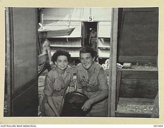LAE, NEW GUINEA, 1945-05-07. GUNNER I. HINCHLIFFE (1) AND PRIVATE D. CHAPLYN (2), PREPARING TO SLUICE OUT THE FLOOR OF THEIR SLEEPING HUT SHORTLY AFTER ARRIVING AT THE AUSTRALIAN WOMEN'S ARMY ..