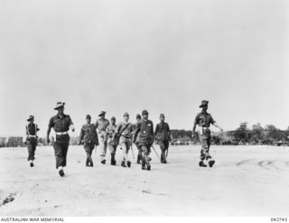 Cape Wom, Wewak, New Guinea. 1945-09-13. Lieutenant General Hatazo Adachi, General Officer Commanding XV111 Japanese Army, being escorted down the airstrip on his way to the surrender ceremony