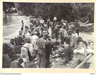 BOUGAINVILLE. 1945-10-01. JAPANESE PATIENTS LINED UP ON THE BEACH WHILE MEMBERS OF FIELD SECURITY SECTION SEARCH THEIR PERSONAL GEAR FOR WEAPONS. ALL MEDICAL CASES ARE BEING EVACUATED TO THE NEWLY ..