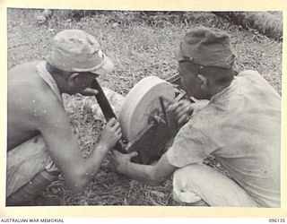 MUSCHU ISLAND, NEW GUINEA. 1945-09-11. TWO JAPANESE SOLDIERS SHARPENING THEIR KNIVES ON A GRINDSTONE. THE ISLAND IS NOW OCCUPIED BY HEADQUARTERS 6 DIVISION AND THE JAPANESE ARE ENGAGED ON BUILDING ..