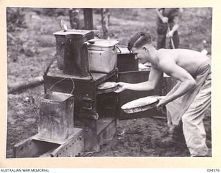 BOUGAINVILLE. 1945-07-19. SAPPER F. MORRIS, AN EX-VICTORIAN JOCKEY, NOW COOKS FOR 15 FIELD COMPANY, ROYAL AUSTRALIAN ENGINEERS. HE IS SHOWN TAKING PEACH PIES FROM HIS CAMP OVEN AT COMPANY ..