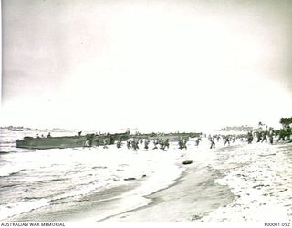 THE SOLOMON ISLANDS, 1945-01-13. GENERAL VIEW OF A BOUGAINVILLE ISLAND BEACH AS TROOPS COME ASHORE FROM LANDING CRAFT WITH SHIPS STANDING OFFSHORE. (RNZAF OFFICIAL PHOTOGRAPH.)