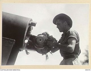 BOIKEN, NEW GUINEA, 1945-07-18. BOMBARDIER A.B. CAMERON, 2/2 FIELD REGIMENT ROYAL AUSTRALIAN ARTILLERY, CLEANING THE BREECH- RING OF A 155 MM M1 "LONG TOM" GUN