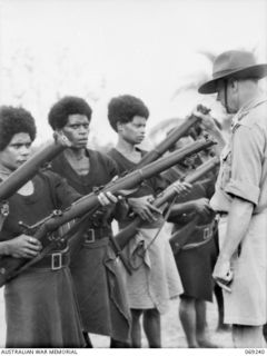 MENDAROPU, NEW GUINEA. 1942-10. P391 CAPTAIN B.W. FAITHORN, AUSTRALIAN AND NEW GUINEA ADMINISTRATION UNIT INSPECTING THE RIFLES OF MEMBERS OF THE ROYAL PAPUAN CONSTABULARY