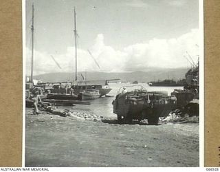 LAE, NEW GUINEA. 1944-06-14/02. A SECTION OF THE WATERFRONT SHOWING A UNITED STATES ARMY AMPHIBIOUS "DUKW" IN THE FOREGROUND AND THE AK94, A VESSEL OF THE 12TH WATER TRANSPORT OPERATING COMPANY, ..