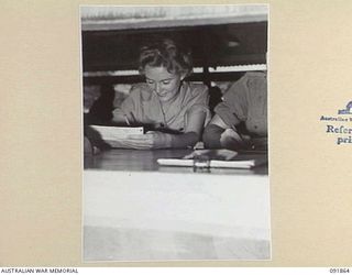 LAE, NEW GUINEA, 1945-05-16. SIGNALMAN M. ATTERY, SIGNAL CLERK AT HEADQUARTERS FIRST ARMY, LEARNS THE ROUTINE OF HER NEW JOB. AUSTRALIAN WOMEN'S ARMY SERVICE PERSONNEL ARE TAKING OVER THEIR NEW ..