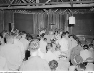 MADANG, NEW GUINEA. 1944-12-25. RAAF PERSONNEL RECEIVING HOLY COMMUNION AT MIDNIGHT MASS FOR CHRISTMAS IN THE RAAF MEMORIAL CHAPEL FROM CLEMENT VAWDREY