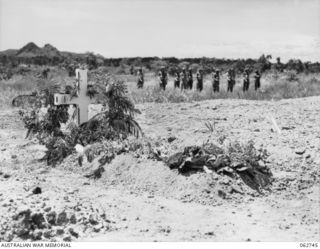 BOMANA WAR CEMETERY, PAPUA, NEW GUINEA. 1943-12-29. CLOSE UP OF THE GRAVE OF PENDIL A. RAYNER, AN AUSTRALIAN WAR CORRESPONDENT WHO WAS KILLED IN AN AIRCRAFT CRASH, SHOWING FUNERAL PARTY FROM THE ..